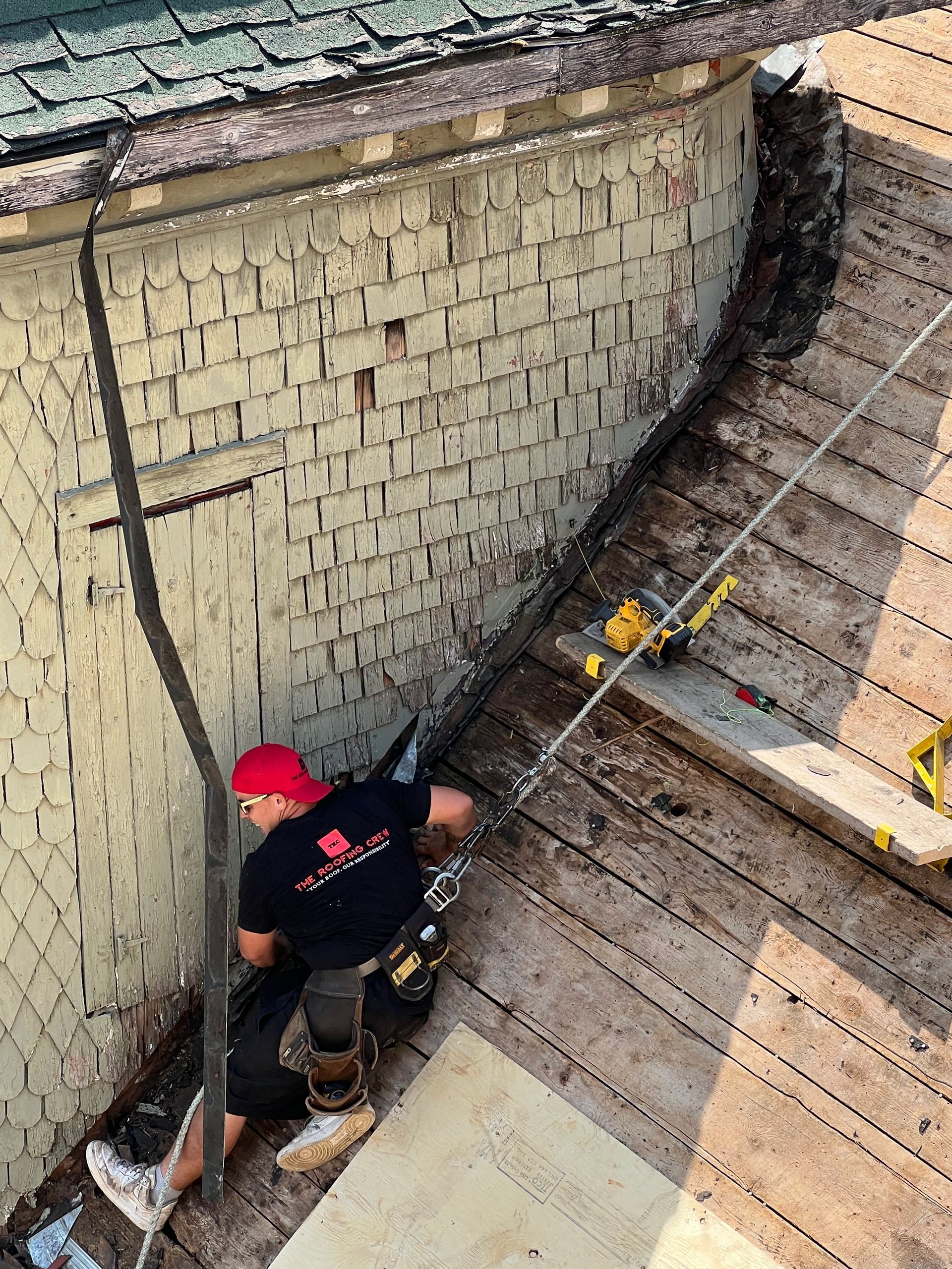 A man in a red hat is working on a roof.