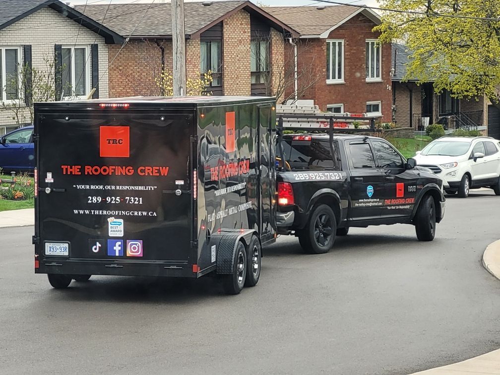 A truck pulling a trailer that says the roofing crew
