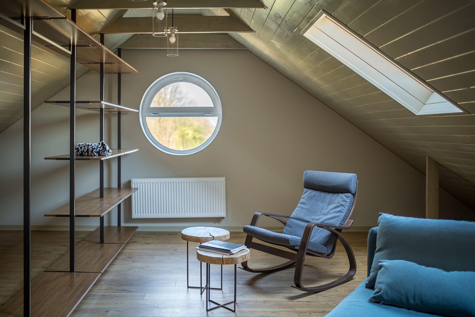 There is a rocking chair in the attic with a round window.