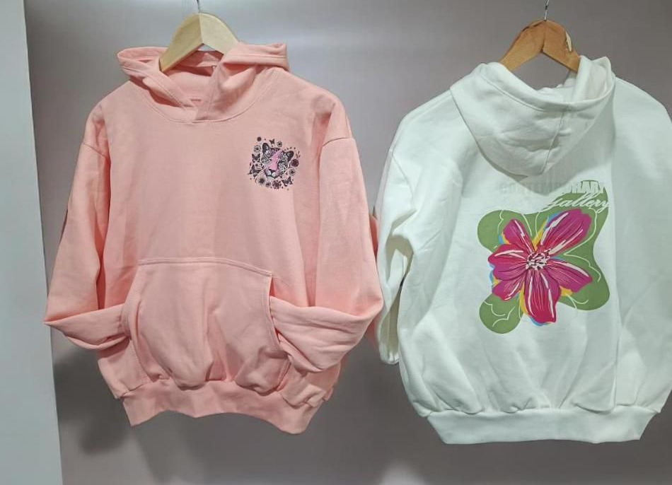 Dos sudaderas con capucha en perchas: una rosa con un pequeño estampado en el pecho