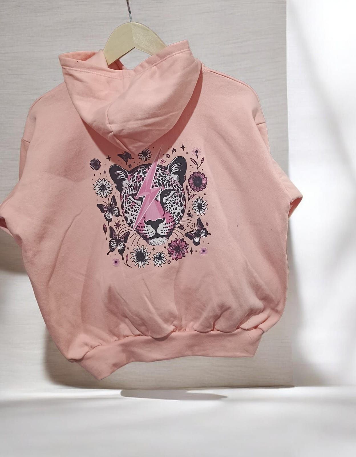 Dos sudaderas con capucha en perchas: una rosa con un pequeño estampado en el pecho