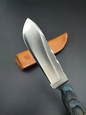 A sharpened fixed-blade knife with a grey layered handle, positioned diagonally above its tan leather sheath.