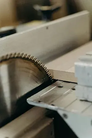 A close-up view of a circular saw blade cutting into a piece of light-colored wood on a workbench.