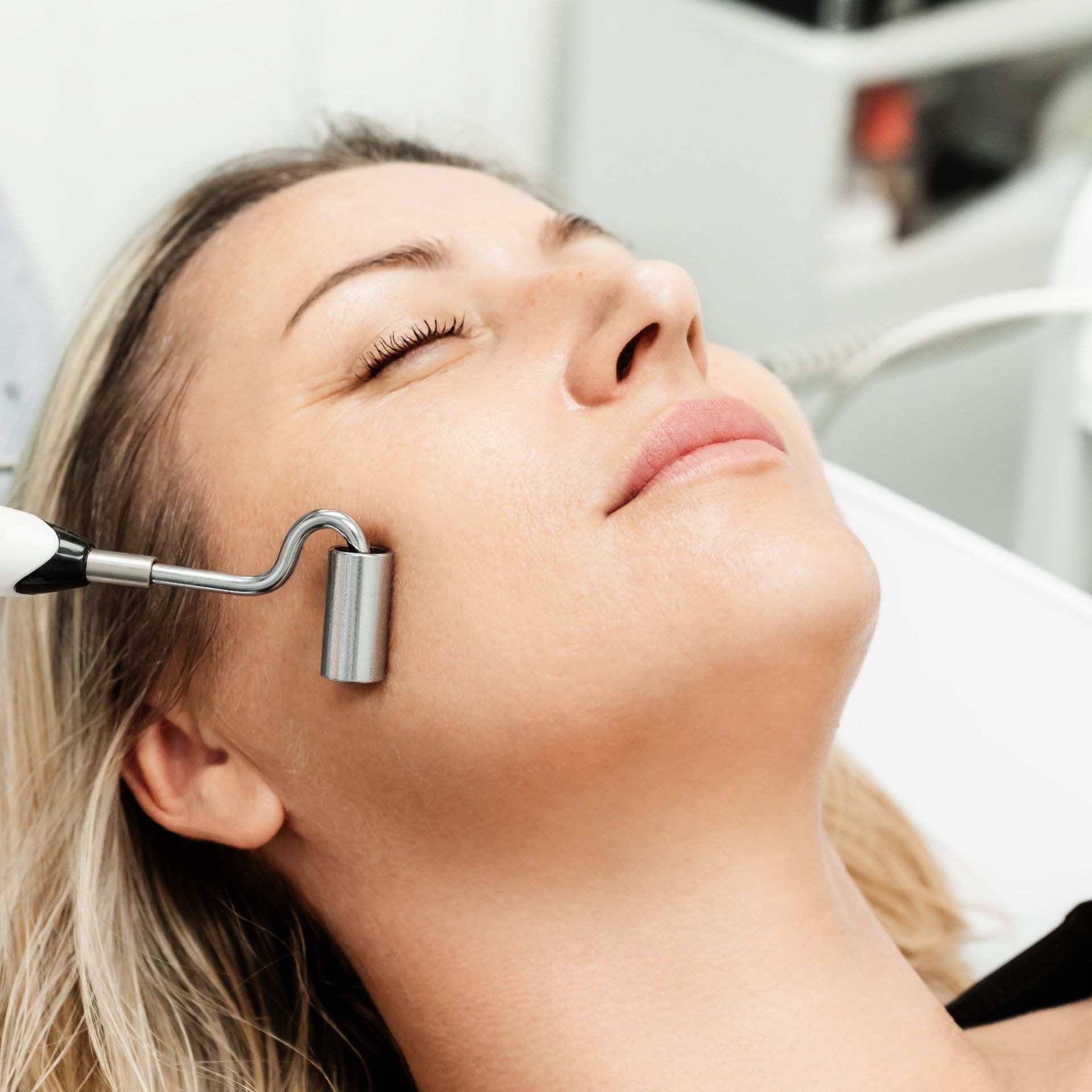 A woman is getting a facial treatment with her eyes closed