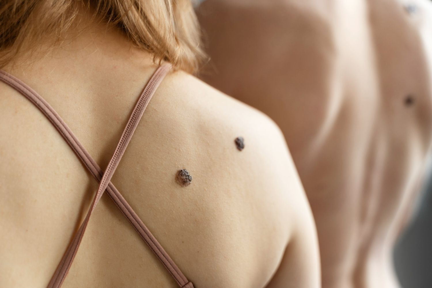 A woman with a ladybug tattoo on her back is looking at herself in the mirror.