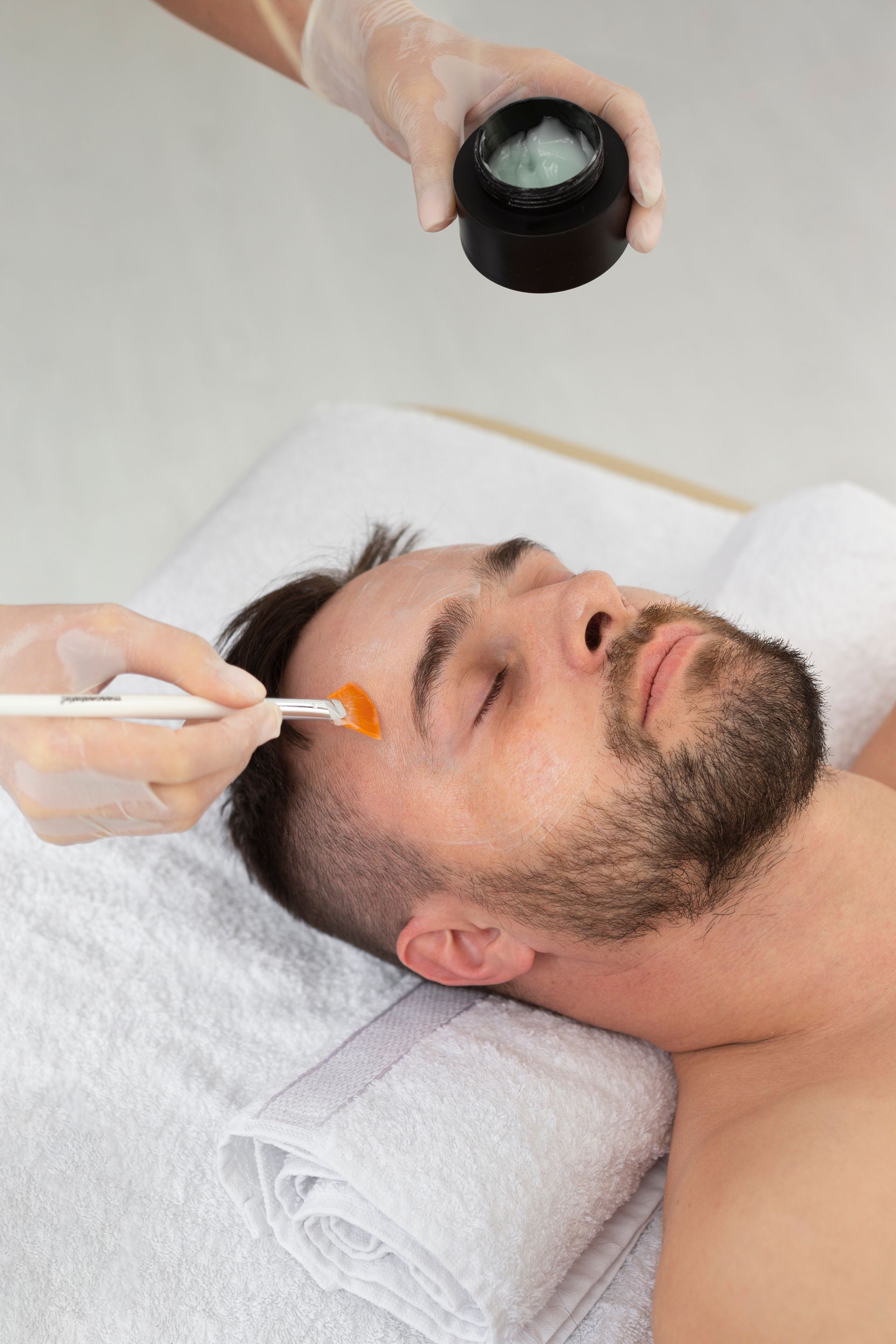 a man with a beard is getting a facial treatment at a spa .