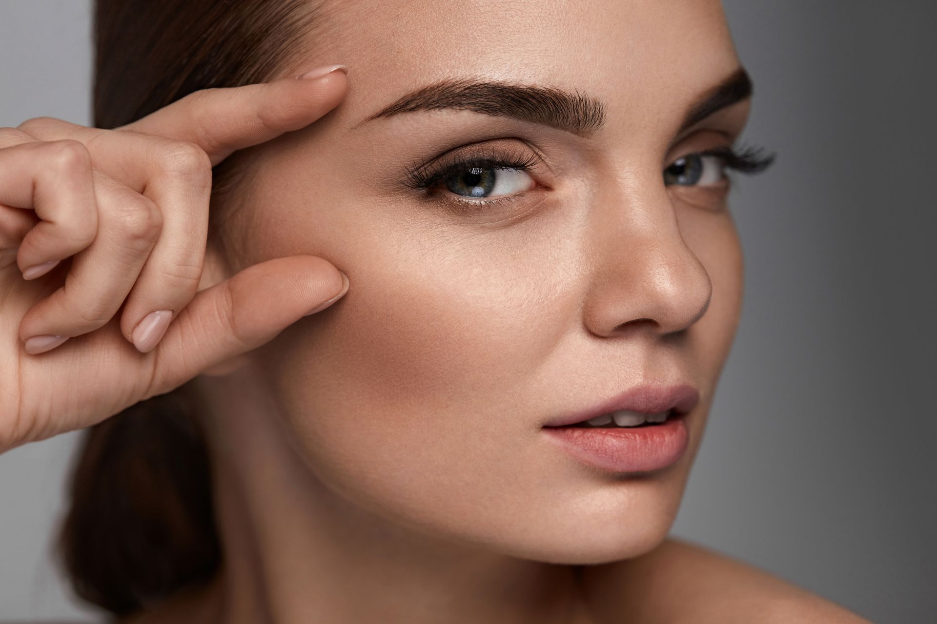 A woman is touching her eyebrows with her finger.