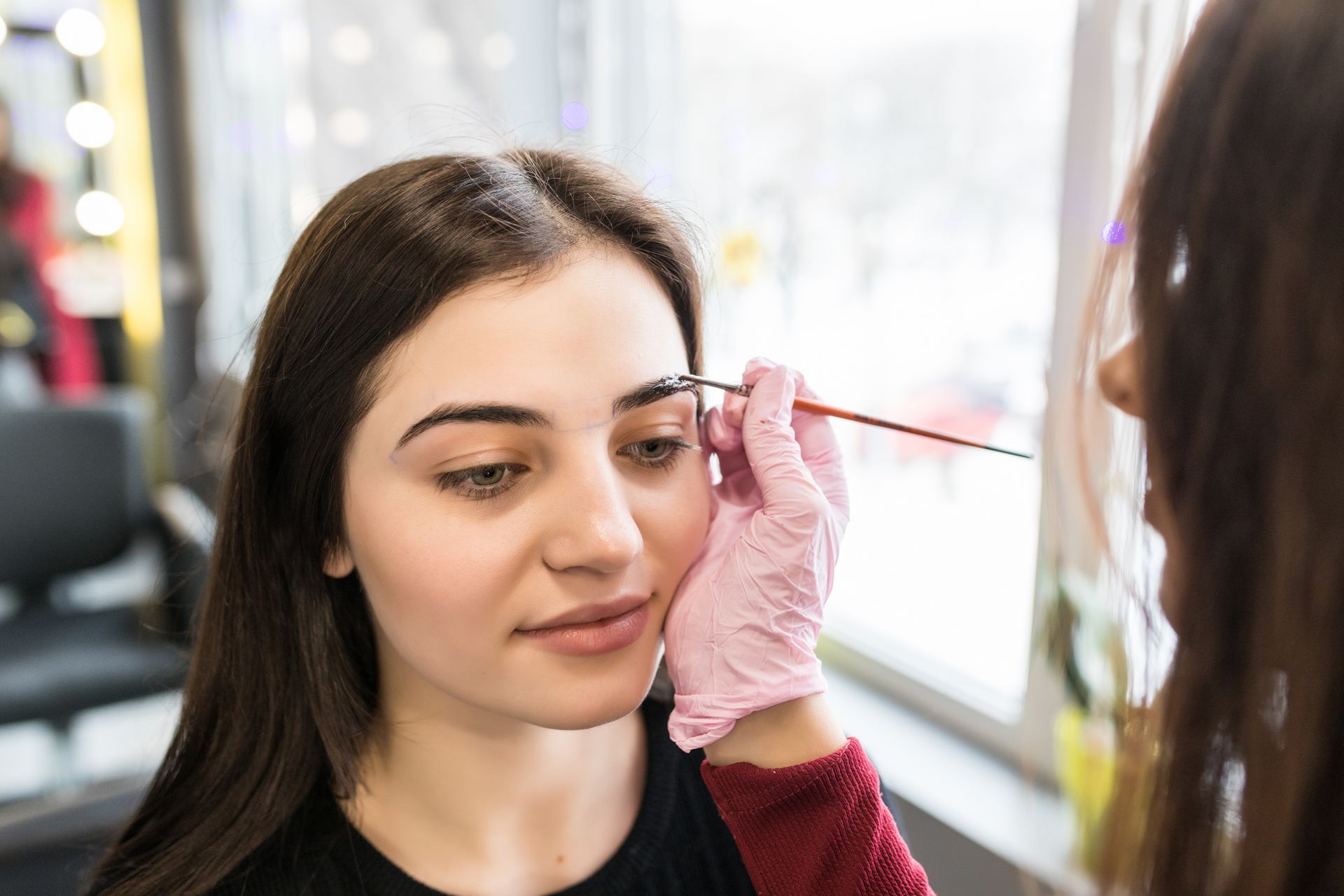 A woman is getting her eyebrows done in a salon.