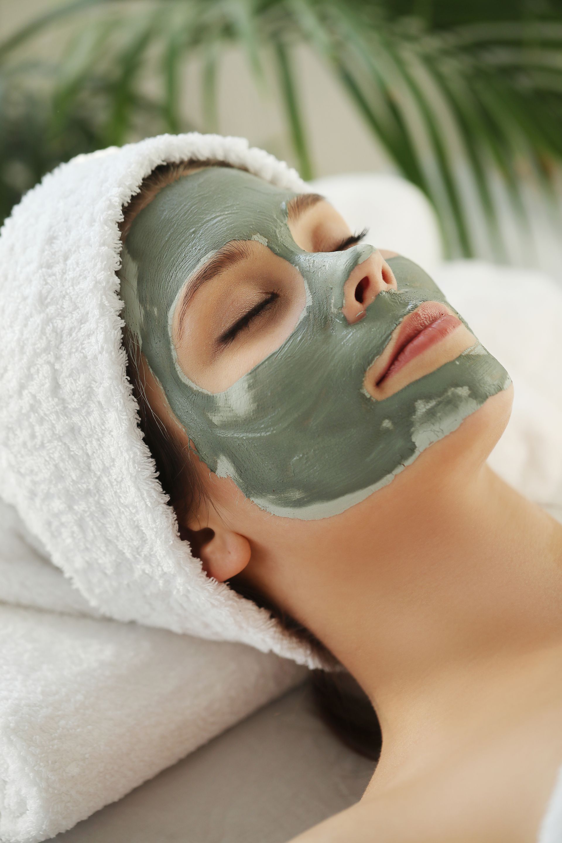 a woman is laying on a bed with a clay mask on her face .
