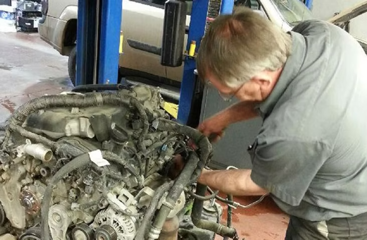 Mechanic working on an engine in a garage. | Acadia Auto Service