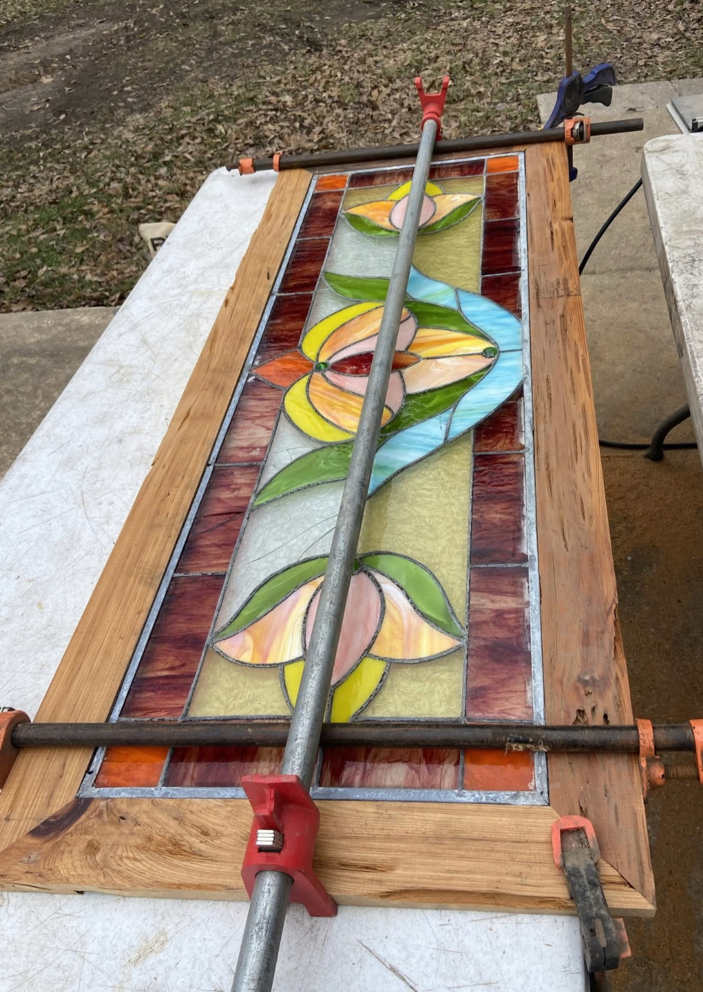 A stained glass window is being glued to a wooden frame.