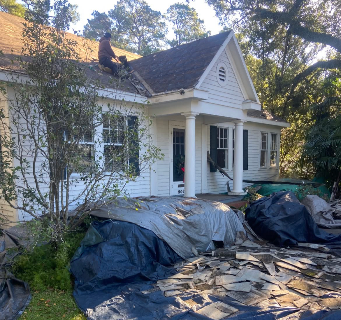 A man is working on the roof of a white house