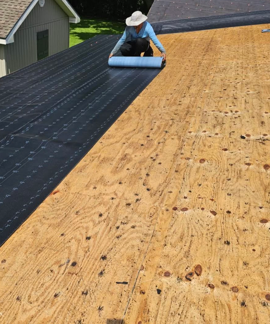 A man is laying plywood on top of a roof.
