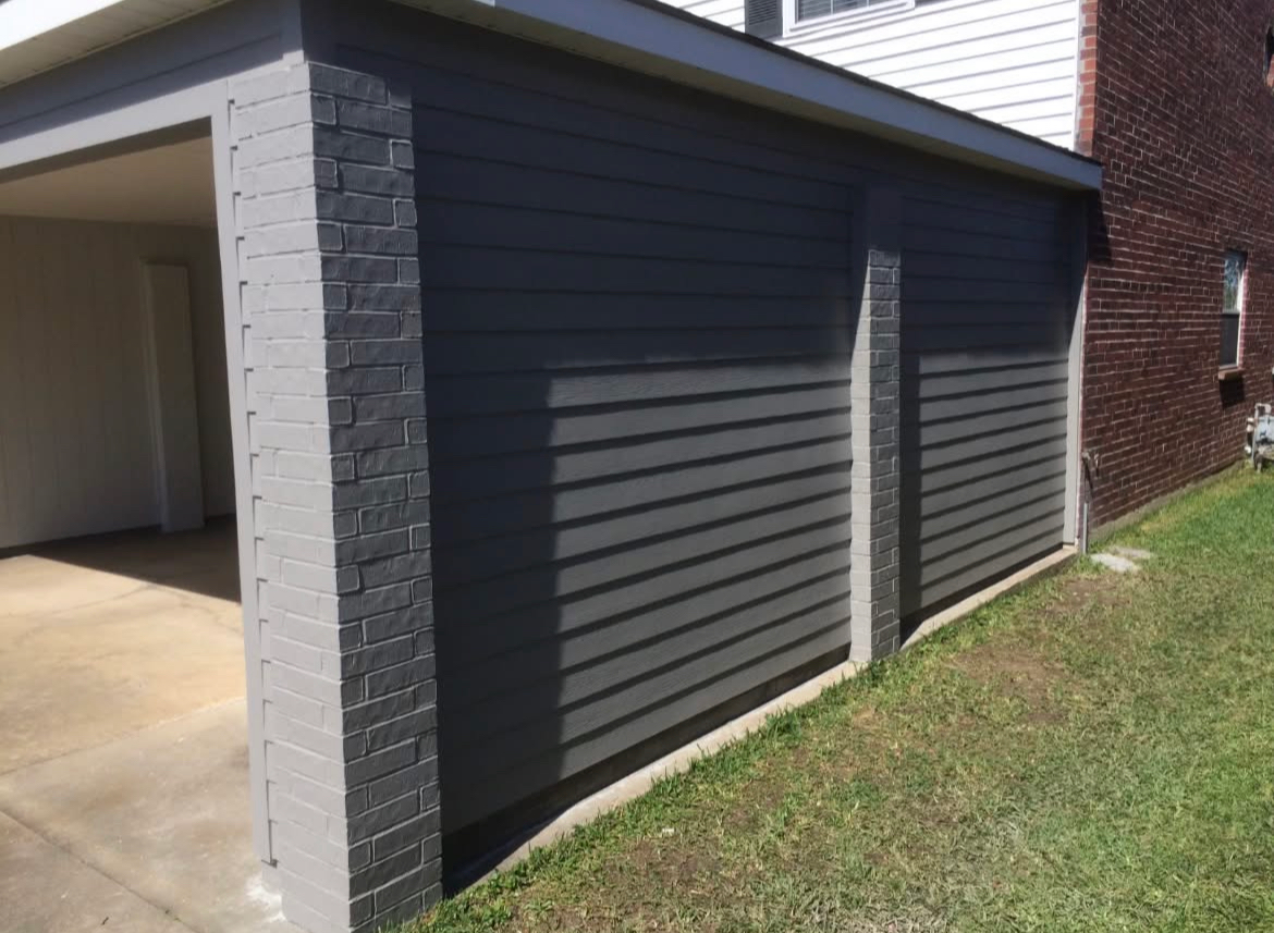 A garage with a brick wall and a gray siding.