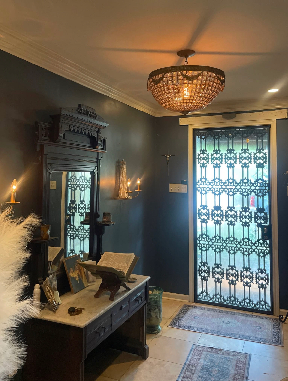 A room with a table and a mirror and a chandelier hanging from the ceiling.