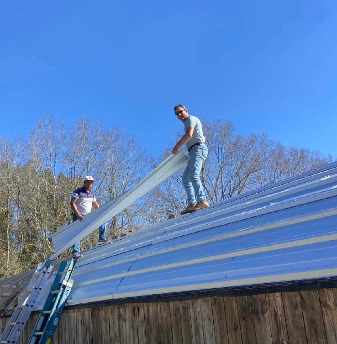Two men are working on the roof of a building.