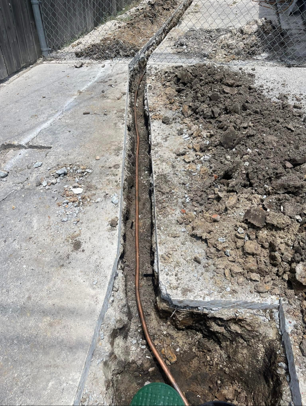 A copper wire is being installed in a hole in the ground.