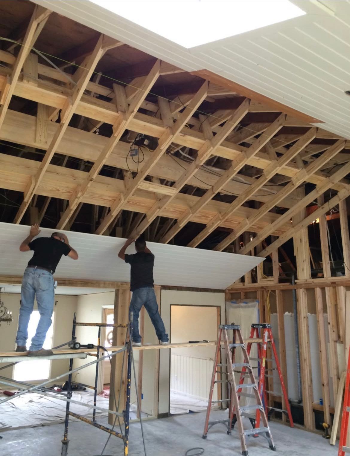 Two men are working on the ceiling of a house
