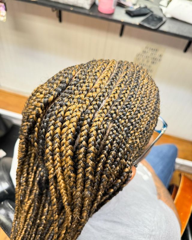 A woman with braids and glasses is sitting in a chair.