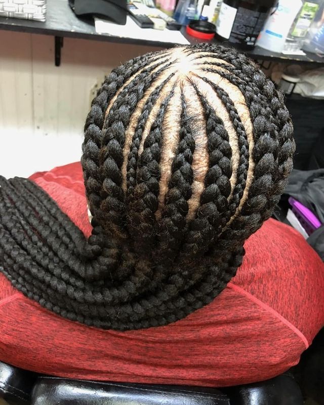 A woman with braids in her hair is sitting on a chair.