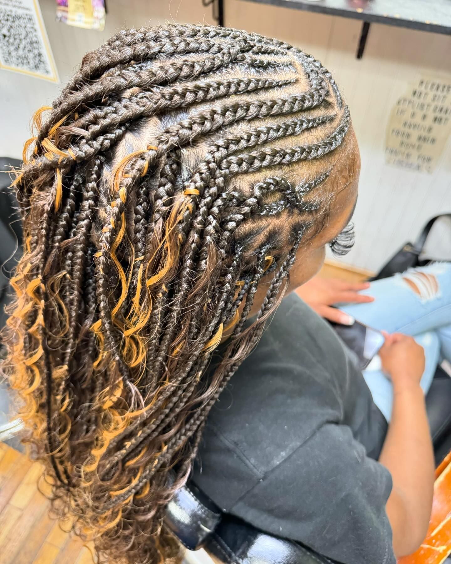 A woman with braids in her hair is sitting in a chair.