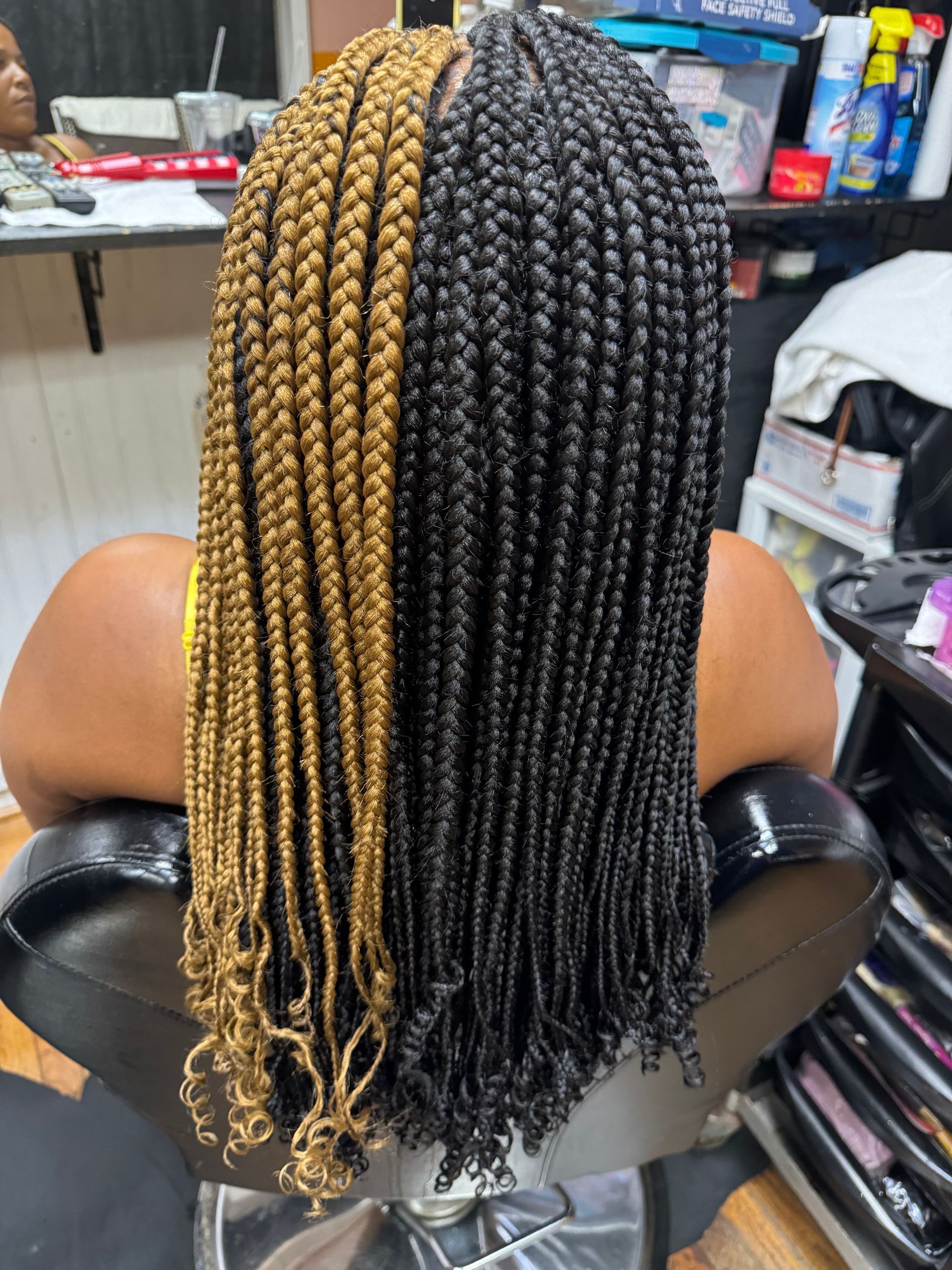 A woman is sitting in a chair with two different colored braids in her hair. | Los Angeles, CA | Aissata & Al Diouma