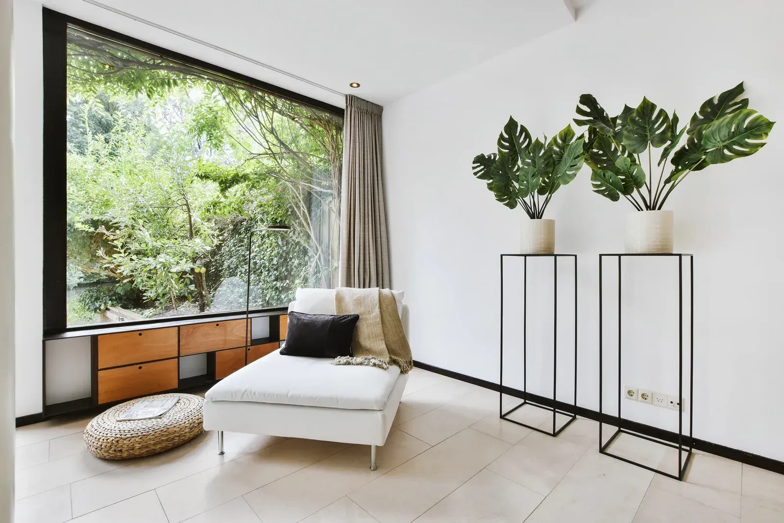 A living room with a large window and a chaise lounge.