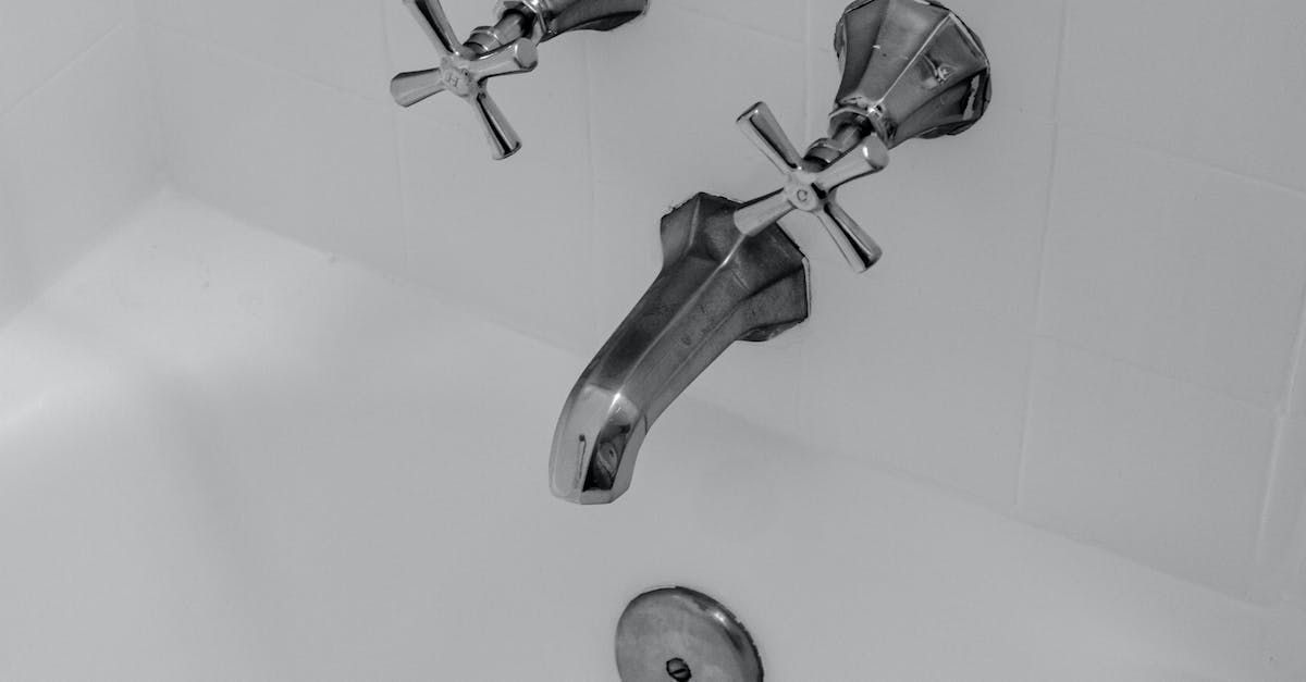 Bathtub faucet and spouts in a white tub. Silver fixtures with cross-shaped handles.