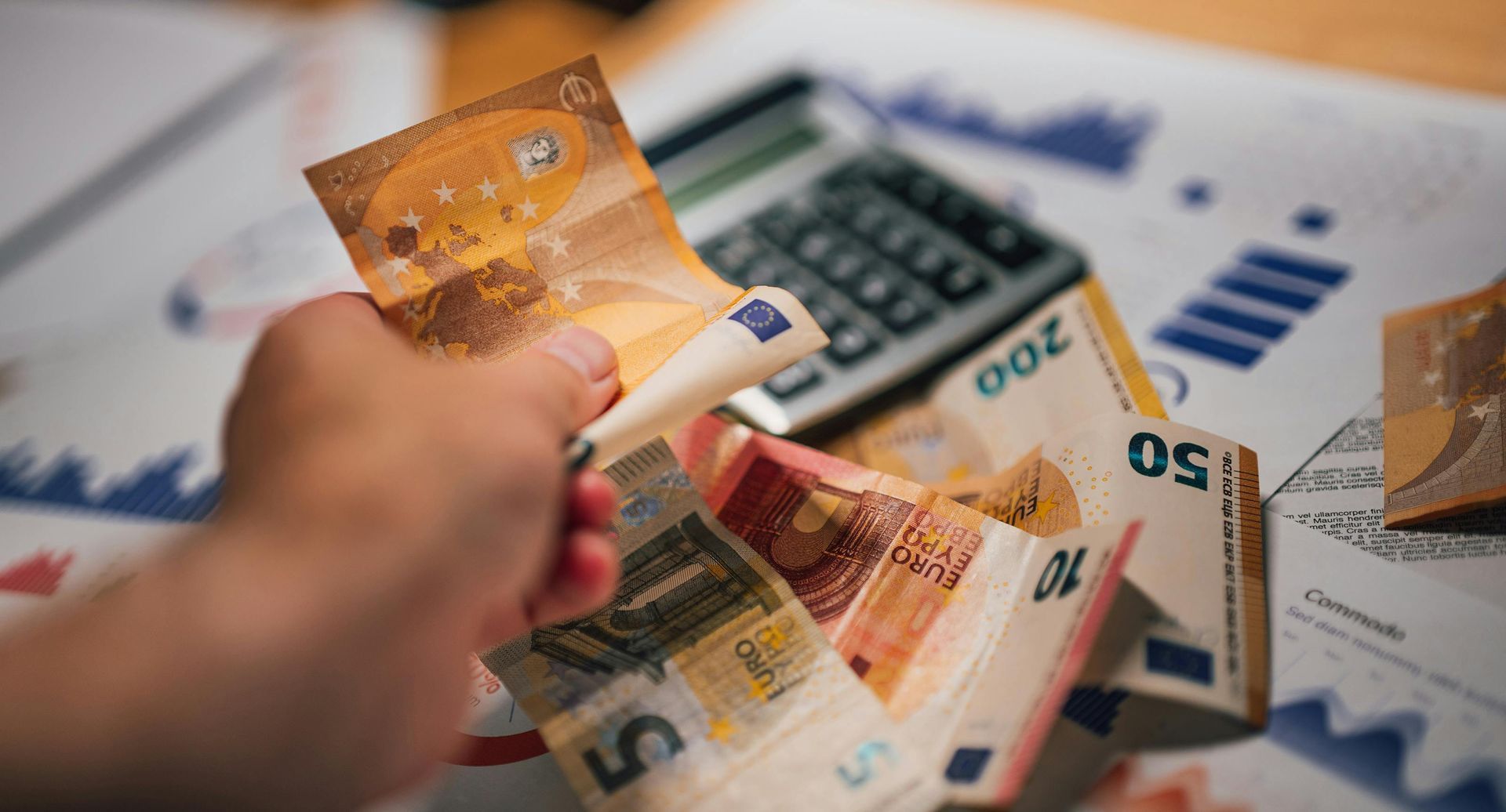 Hand die eurobankbiljetten vasthoudt boven financiële grafieken en een rekenmachine