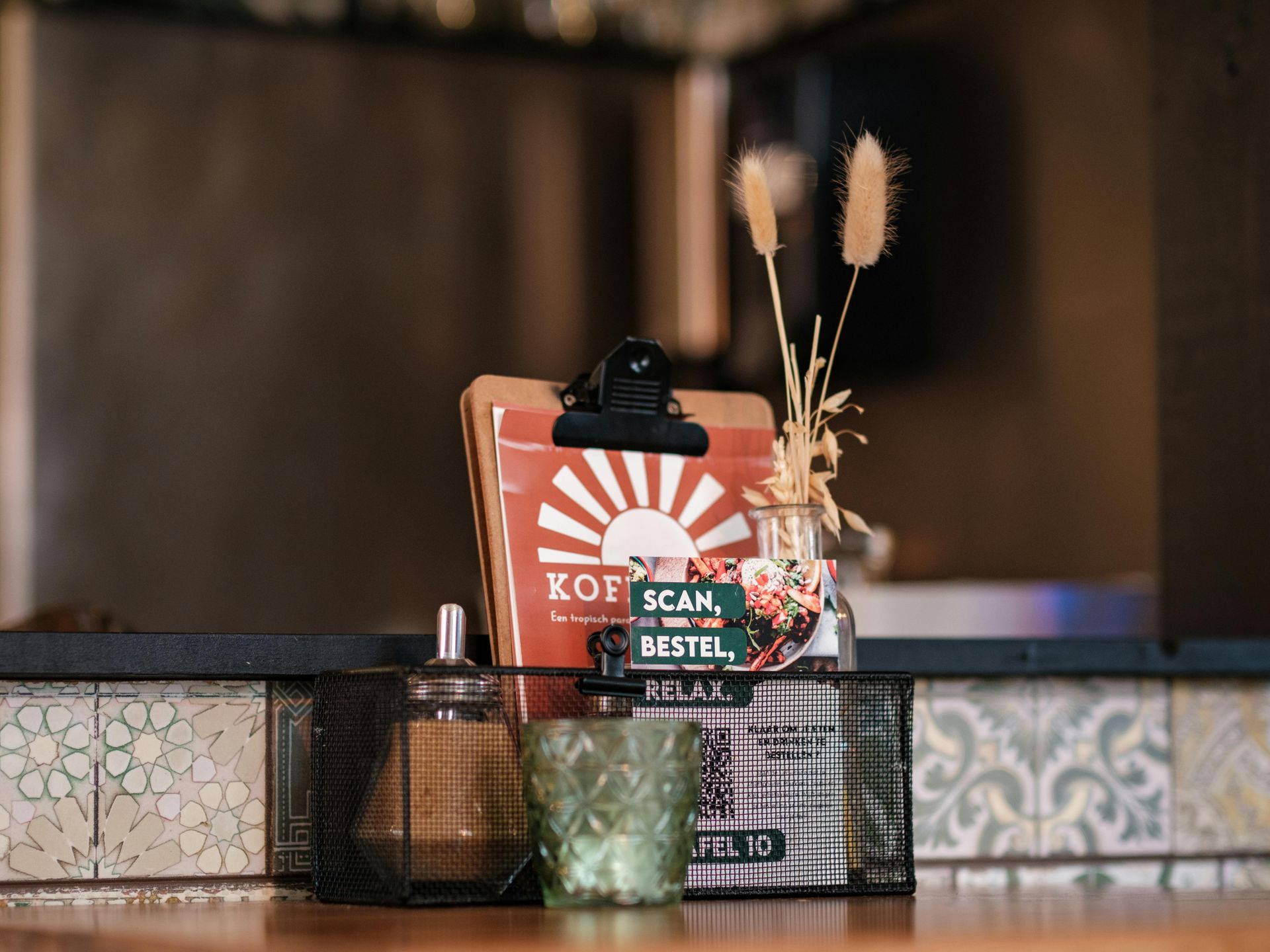 Koffiezak met decoratieve rietjes op een houten toonbank, in een rustieke caféomgeving.