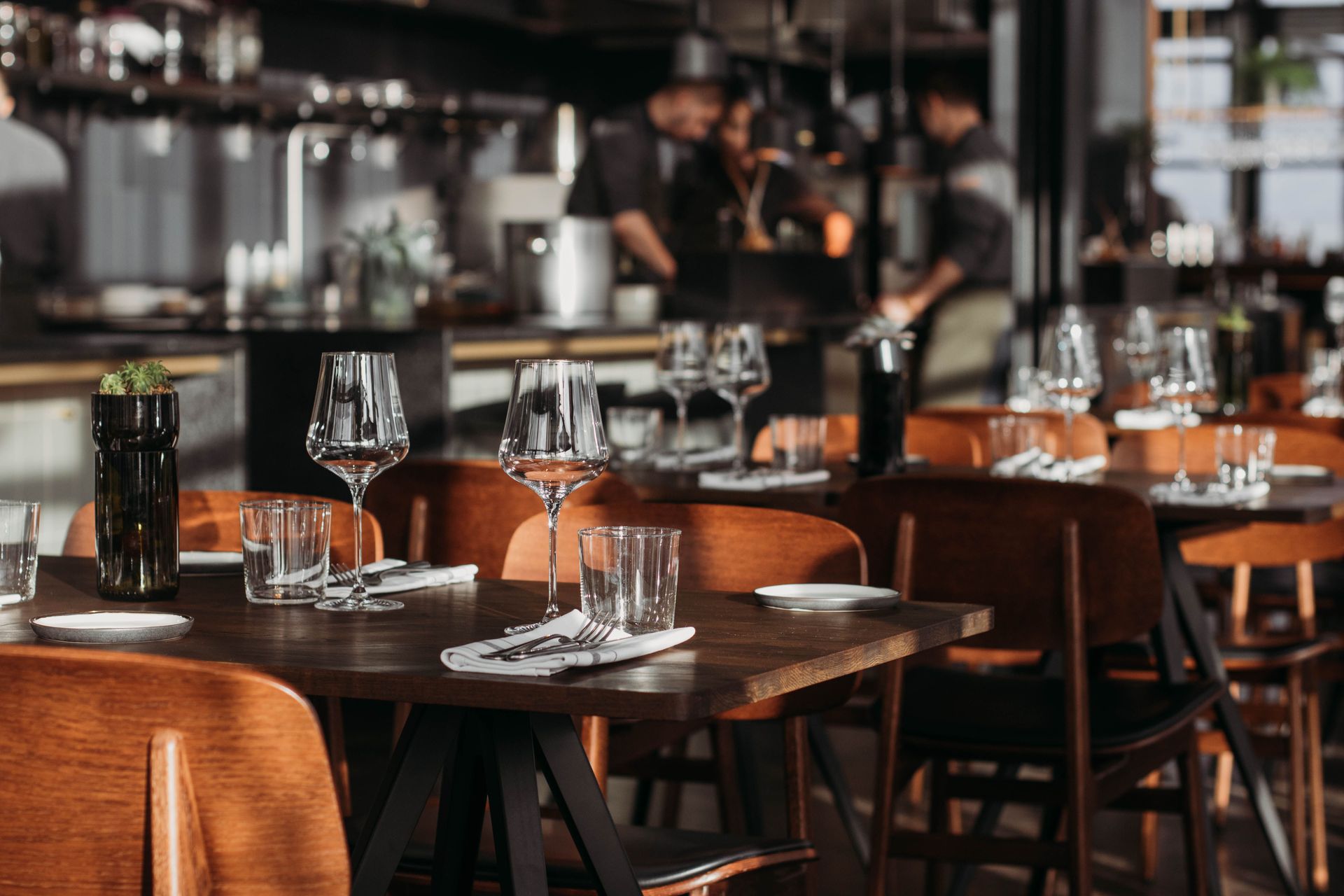 Elegante restaurant eetzaal met gedekte tafels, wijnglazen en warme bruin lederen stoelen.