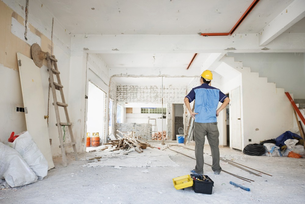 a man in a hard hat is standing in a room under construction .