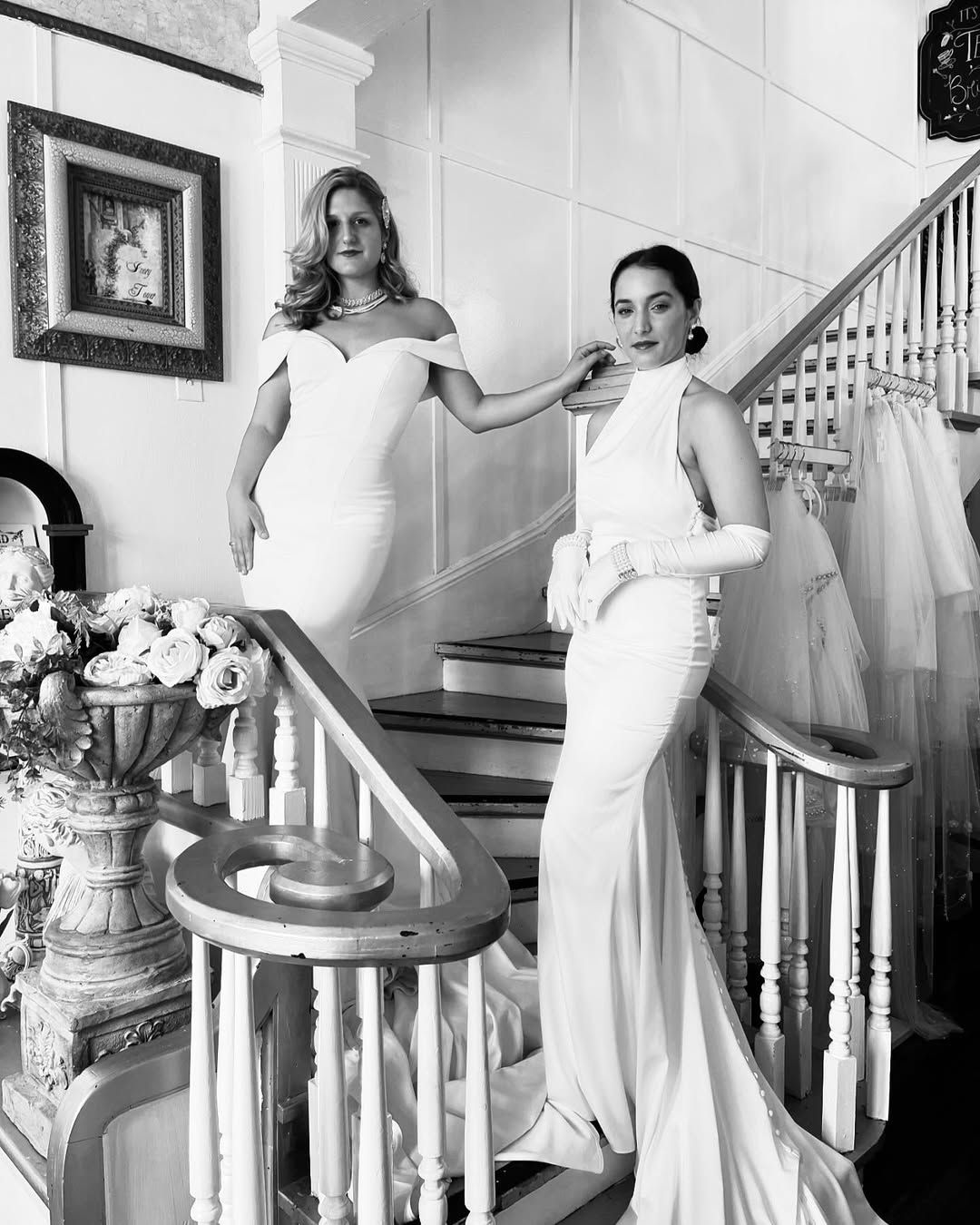 Bride in white dress and veil on ornate stone stairs holding flowers.
