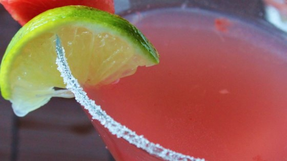 a close up of a watermelon margarita with a slice of lime .