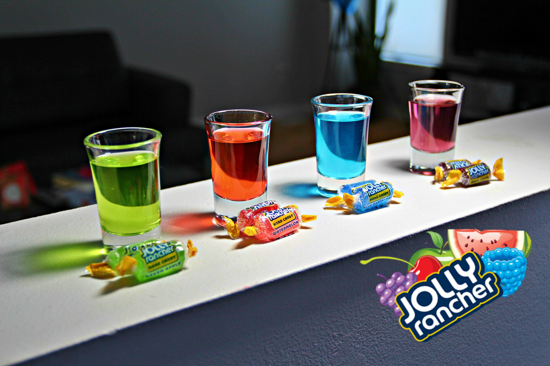 four shot glasses filled with different flavors of jolly rancher candy