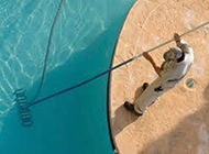 a man is cleaning a swimming pool with a broom .