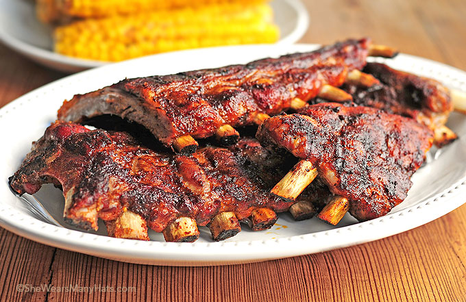 a white plate topped with ribs and corn on the cob .