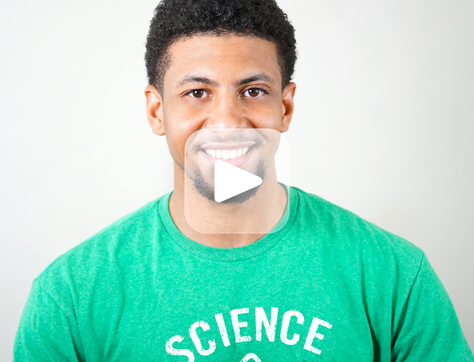 Man in green shirt smiles at the camera. The shirt says 