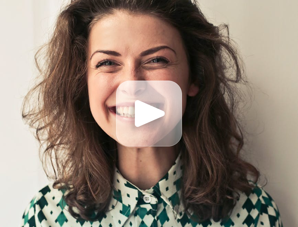 Woman with brown hair smiling broadly, wearing a patterned green shirt.
