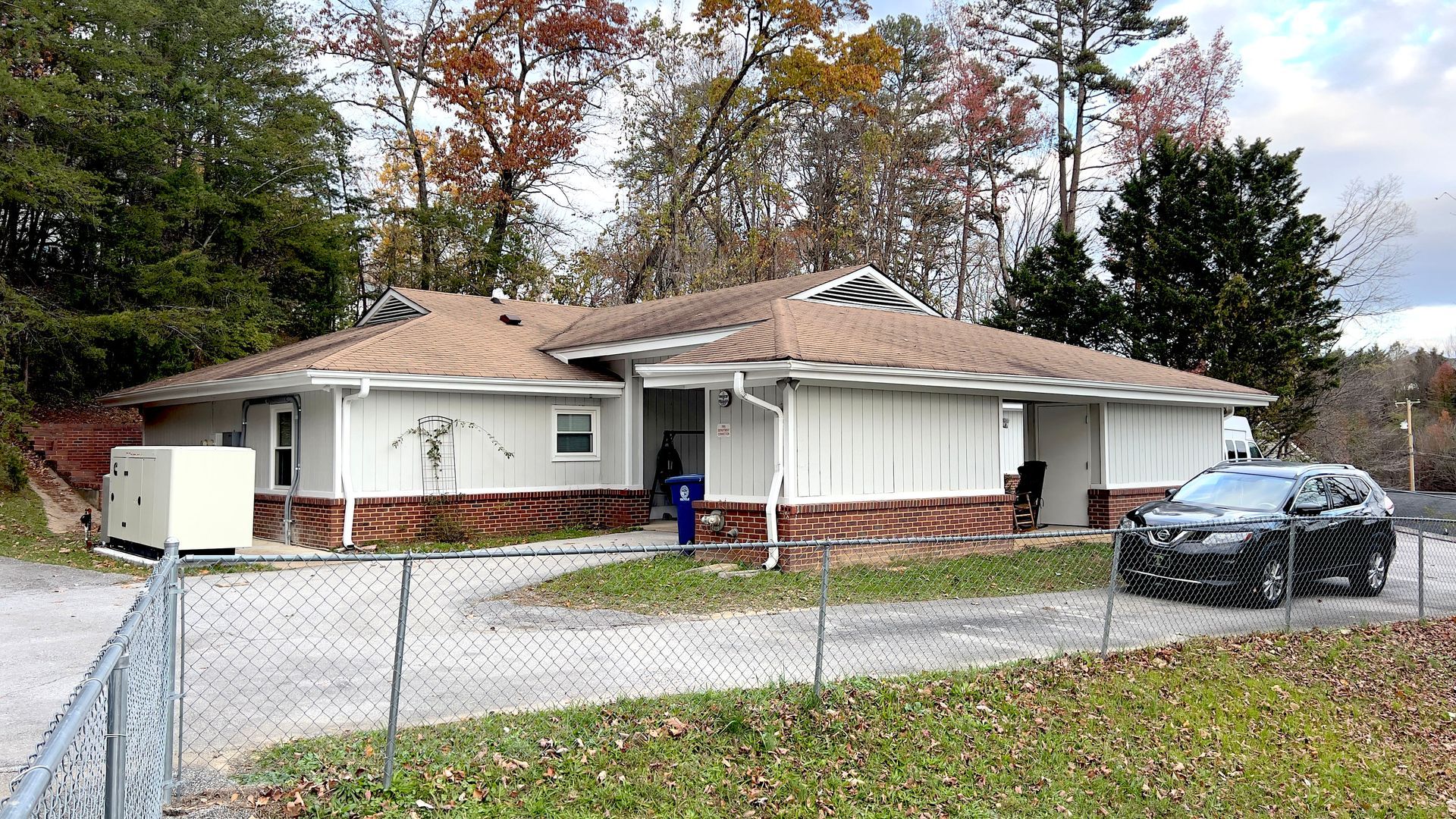 A beige Orange Grove residential home's exterior during daytime. A fence in the foreground, and woods in the background.