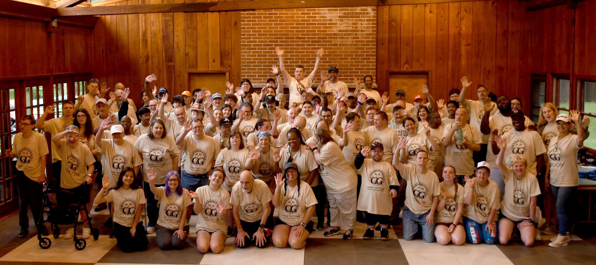 A group of campers and staff from Camp Double G wave in a group photo.