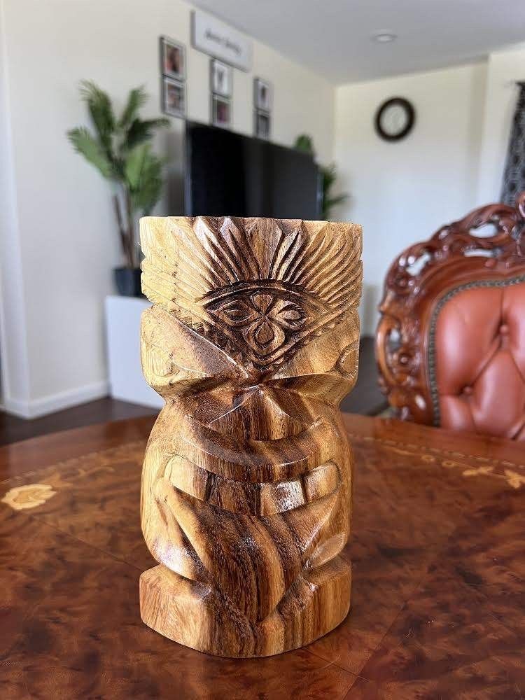 Two Tiki Statues Are Sitting on Top of A Rock Surrounded by Pink Flowers — Aiea, HI — Auvaa Island Made LLC