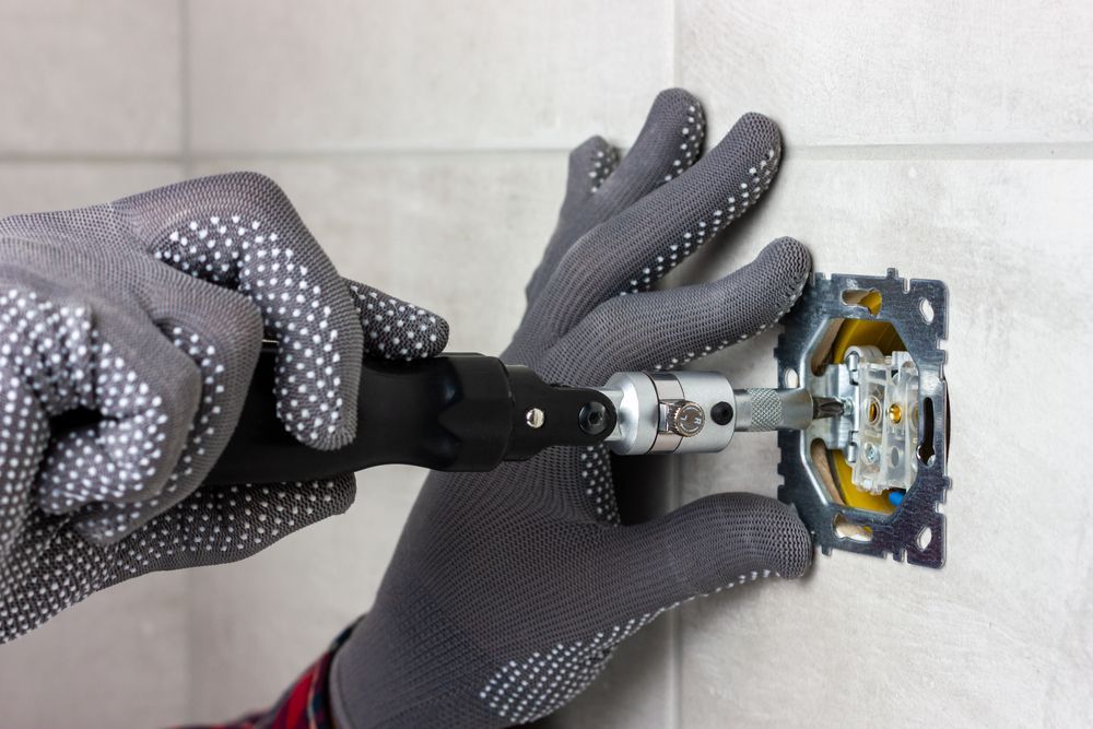 A Person is Installing a Light Switch on a Wall — J.A.F. Electrical Solutions in Kawana, QLD