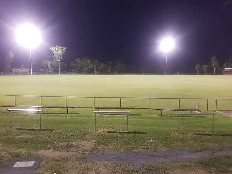 A Baseball Field is Lit Up at Night With a Fence and Benches — J.A.F. Electrical Solutions in Kawana, QLD