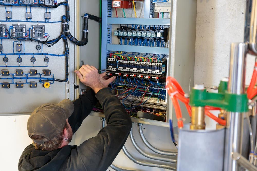 A Man is Working on a Electrical Box in a Room — J.A.F. Electrical Solutions in Kawana, QLD