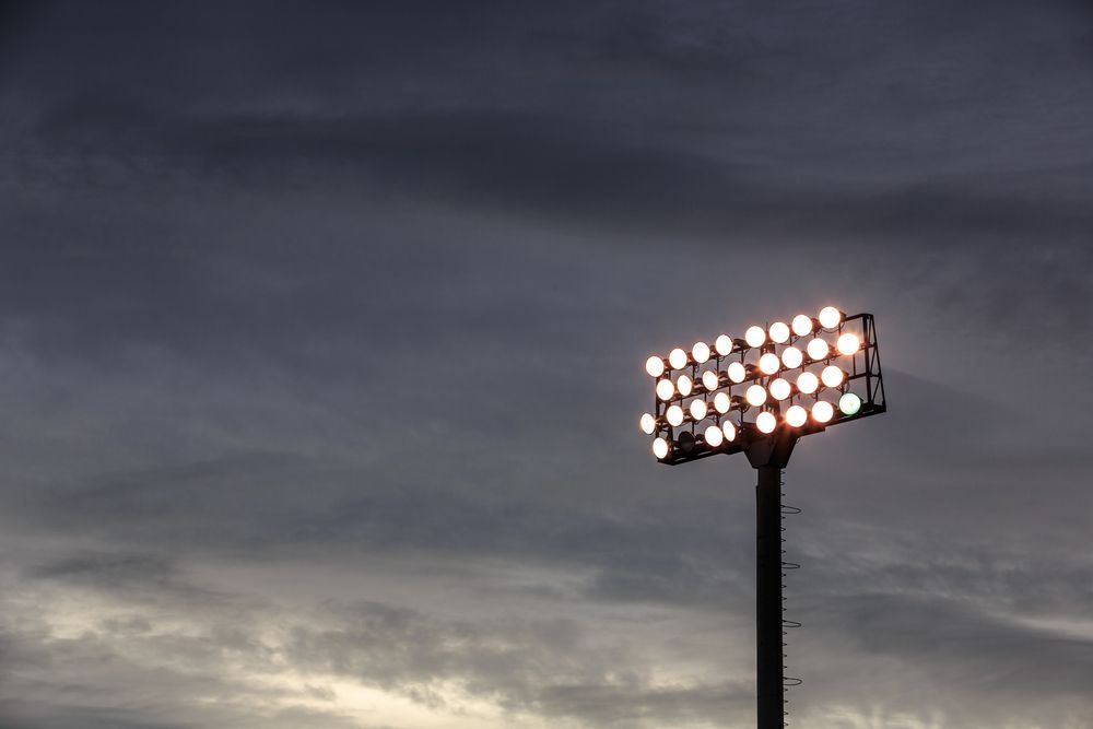 A Stadium Light is Lit Up at Night Against a Cloudy Sky — J.A.F. Electrical Solutions in Yeppoon, QLD