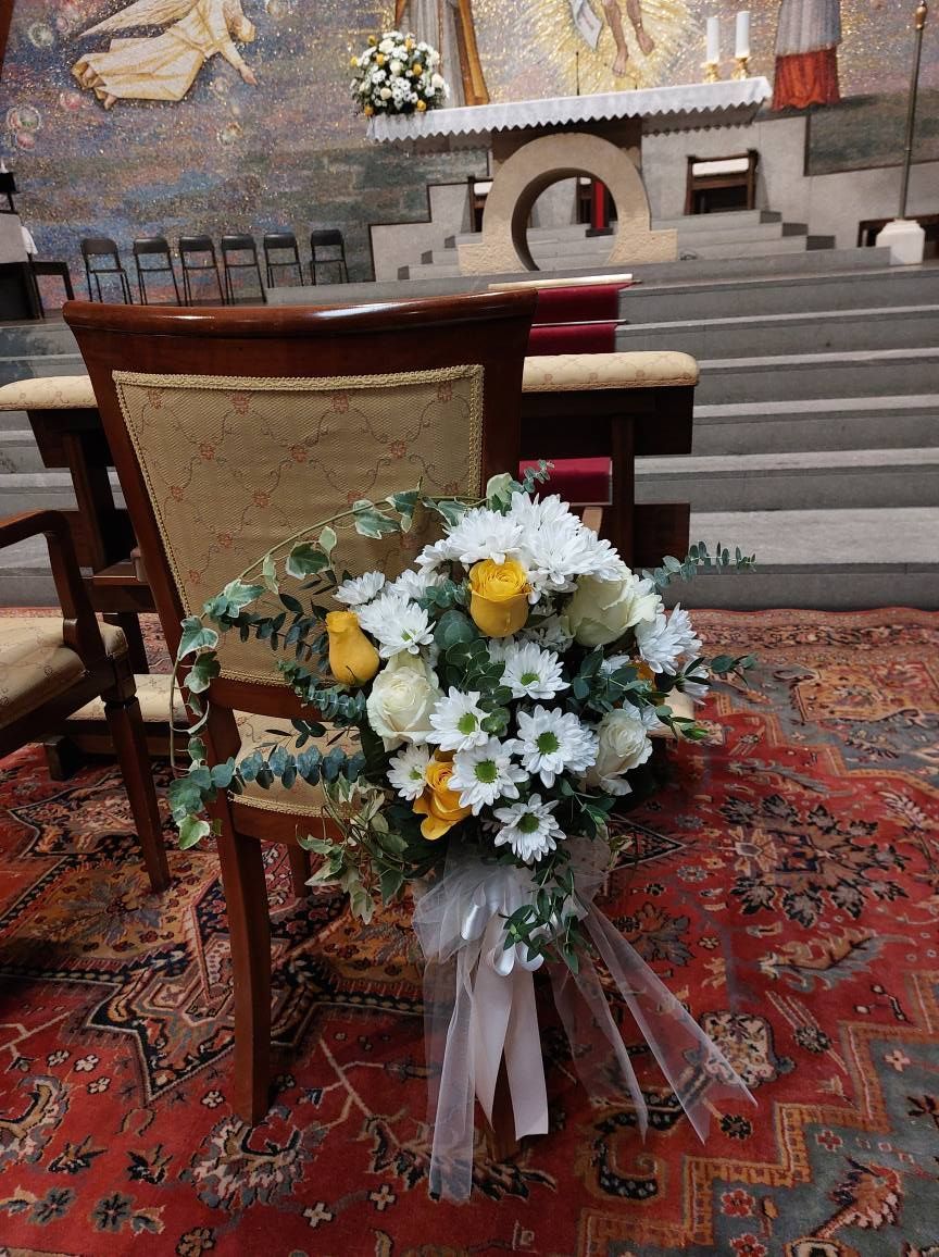Un mazzo di fiori bianchi e gialli su una sedia in una chiesa.