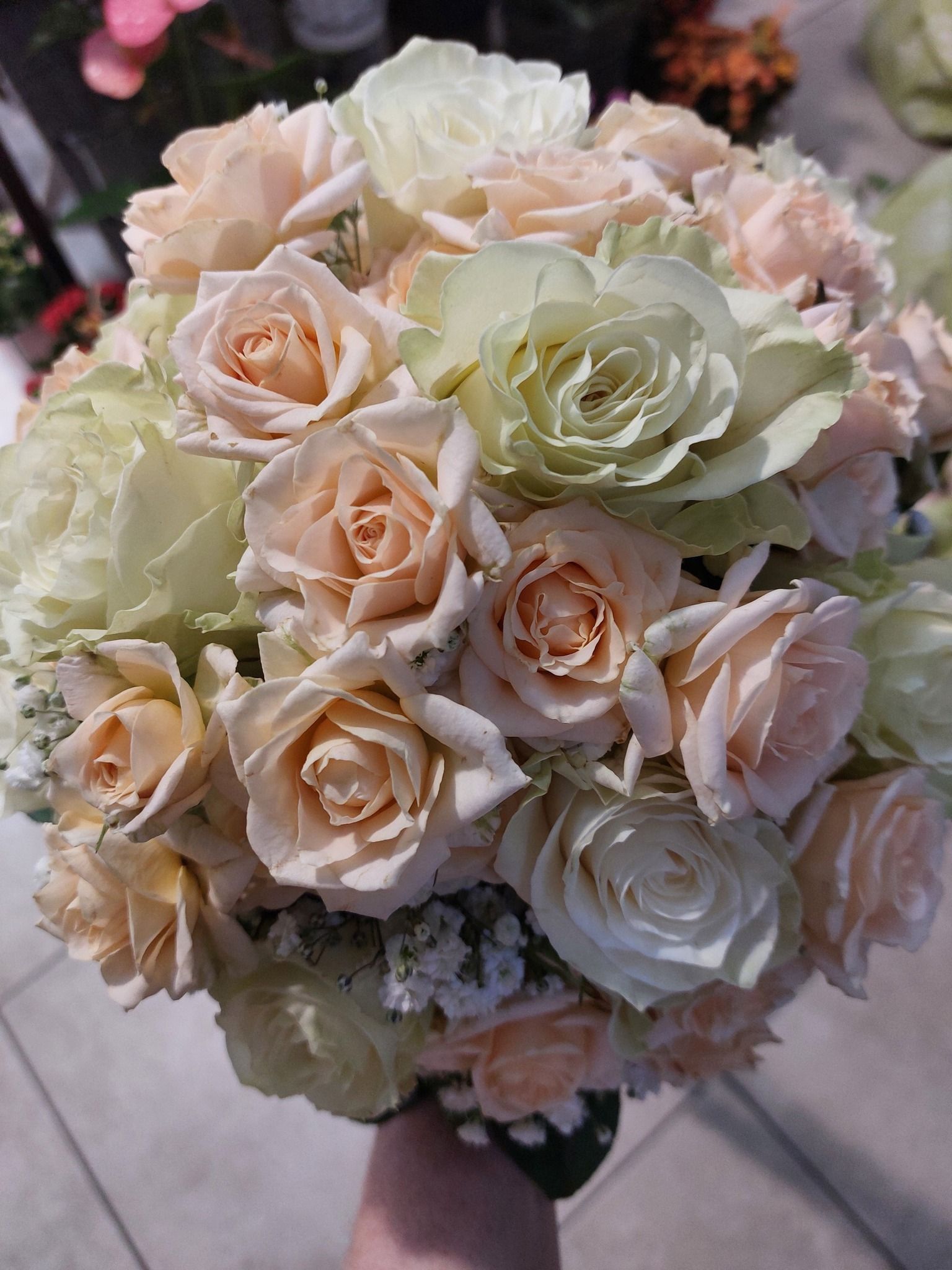 Bouquet di rose color pesca e crema, probabilmente per un matrimonio.