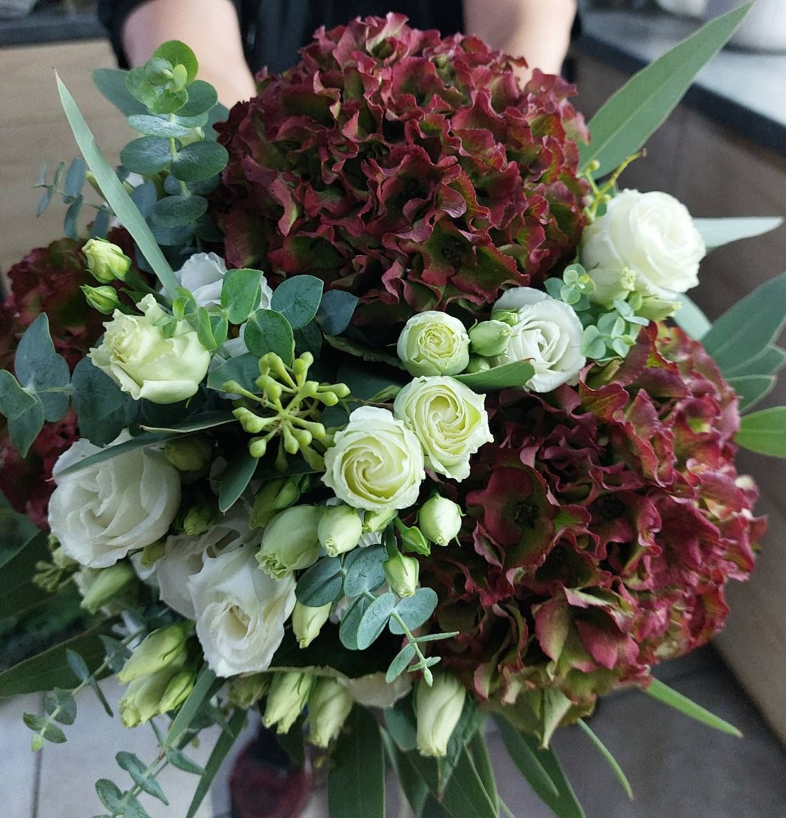 Tavolo bianco decorato con fiori bianchi e crema, verde e portacandele dorati.