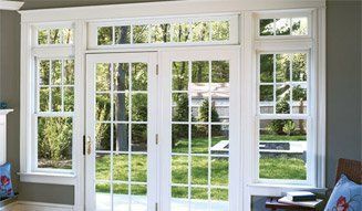 Bright French doors and windows with white trim overlooking a green backyard.
